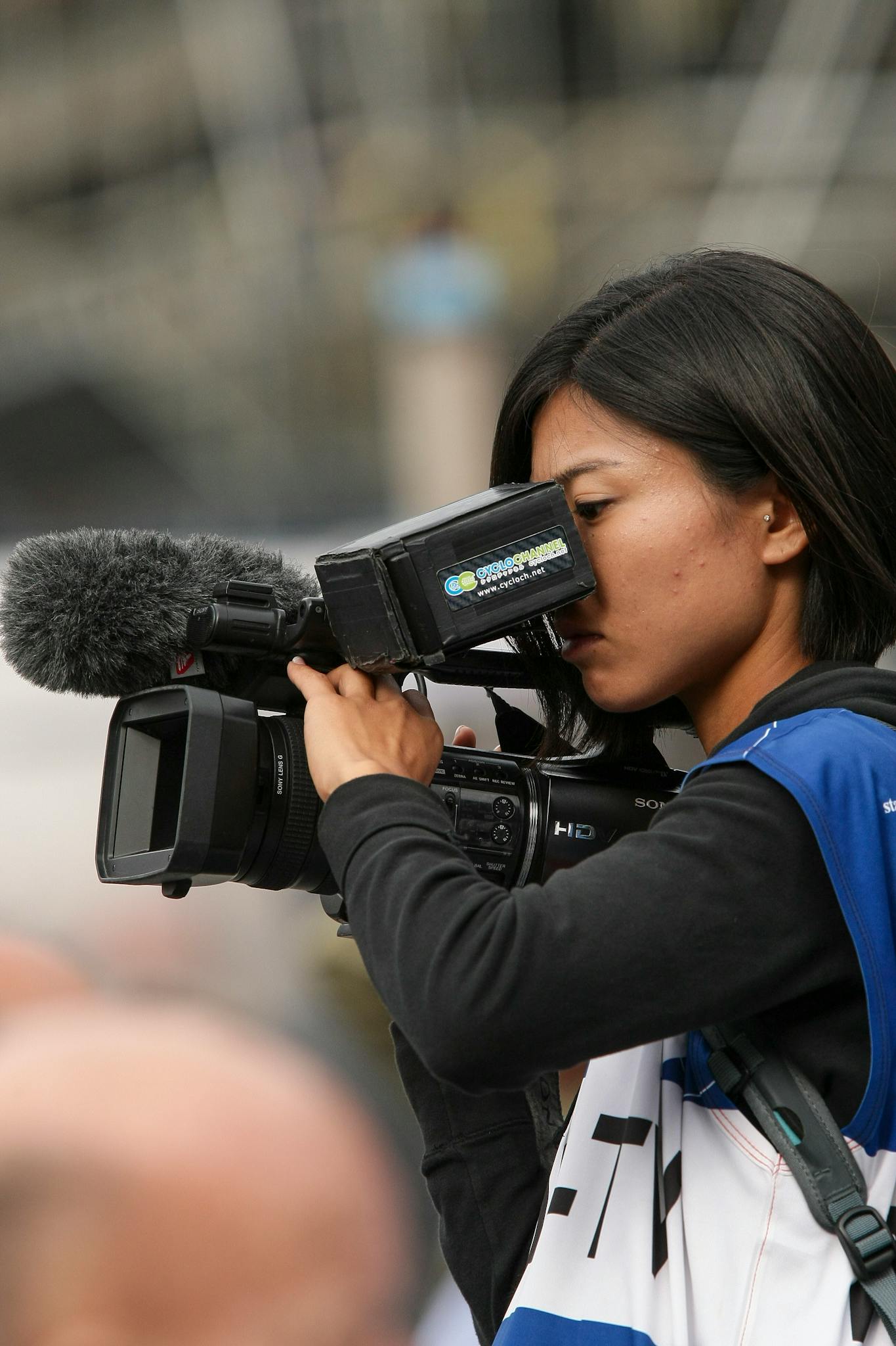 Young female videographer using a professional camera to film an outdoor event.